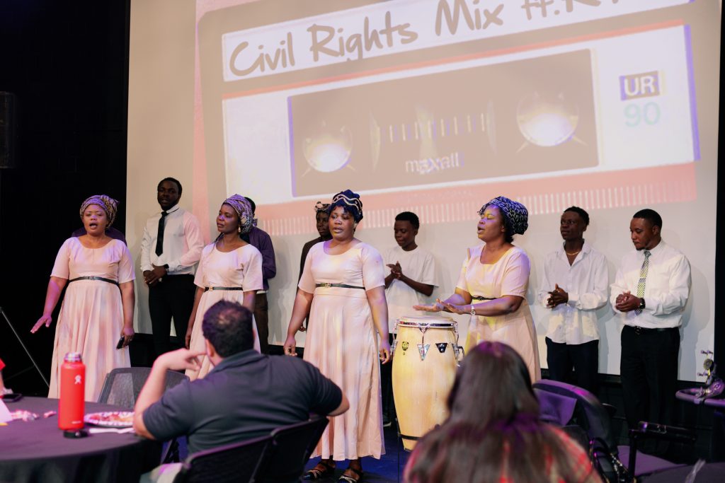 african singing group performing for seated audience
